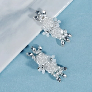 Close-up of handmade bridal shoe clips featuring white resin roses and pearls