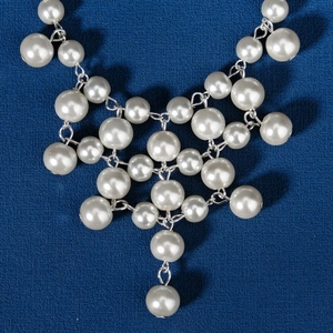 Collier de perles vintage avec liens géométriques argentés sur tissu bleu foncé