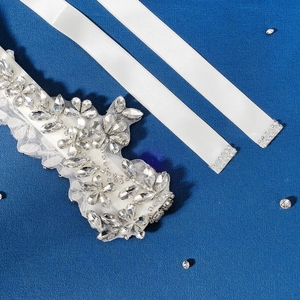 Detailed macro view of crystal rhinestone floral applique on bridal satin sash