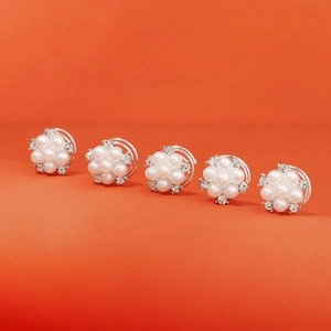 Détail de cinq épingles à cheveux fleurs en perles et cristaux sur fond orange vif