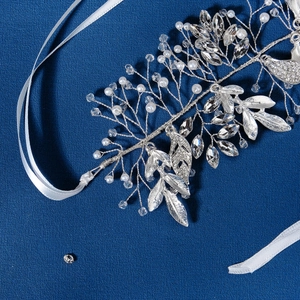Elegant bridal hair band with silver leaves, crystal rhinestones and pearls on blue background