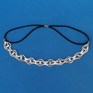 Macro detail of wave-pattern rhinestone headband with silver metal and black elastic band