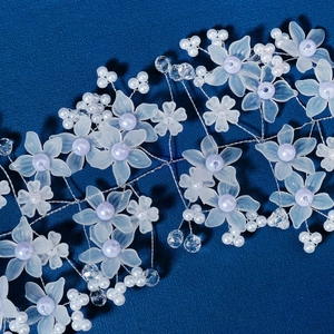 Macro detail of handmade bridal hair vine with blue acrylic flowers and purple pearls