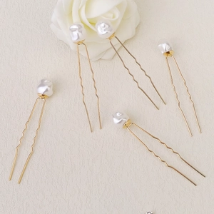 Vue macro de cinq épingles à cheveux dorées en U avec perles baroques blanches