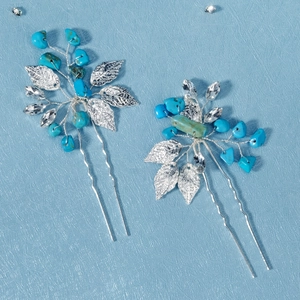 Macro detail of two U-shaped silver hairpins with turquoise stones and crystals