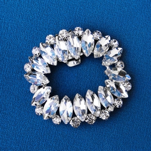 Elegant oval rhinestone shoe clip buckle with crystal accents on navy fabric background