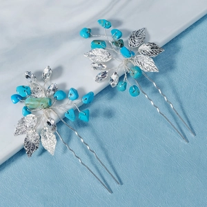 Detailed close-up of handmade U-shaped hair pins with turquoise stones and silver metal leaves