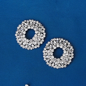 Macro detail of round crystal shoe clips featuring brilliant cut rhinestones on blue fabric