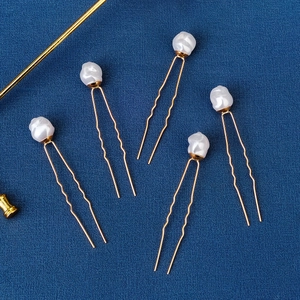 Five pieces of U-shaped golden hair pins with elegant baroque pearls on a navy background