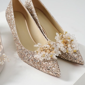 Close-up of champagne glitter bridal heels with intricate crystal beaded floral shoe clips