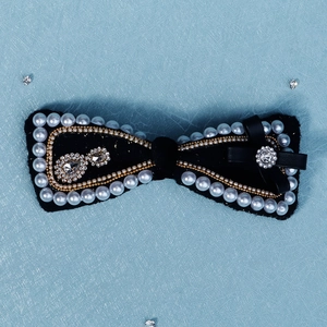 Detailed shot of black velvet bow hair clip with white pearls and sparkling rhinestones