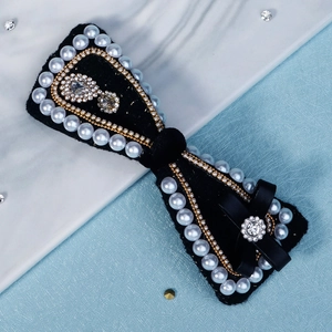 Detail of vintage black velvet bow hair clip with white pearls and rhinestone floral accents