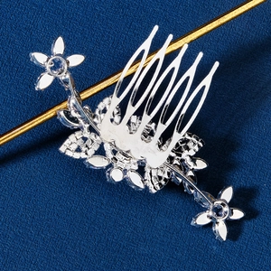 Close-up of silver bridal hair comb with cubic zirconia flowers on dark background