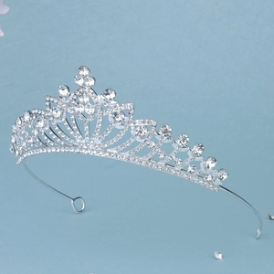 Macro view of silver hollowed-out tiara with sparkling rhinestones on blue background