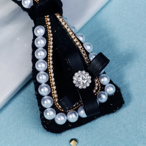 Close-up of black velvet bridal hair clip with pearl trim and rhinestone bow detail