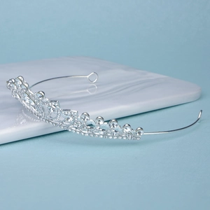 Macro detail of silver wedding crown with hollow heart patterns and sparkling rhinestones