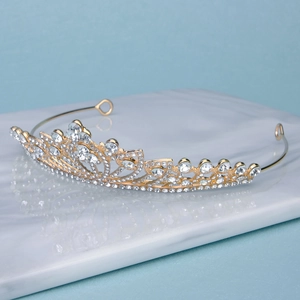 Close-up of golden hollow crown featuring sparkling rhinestones on marble tray