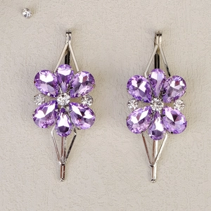 Nahaufnahme eleganter Haarspangen mit lila Kristallblüten aus Silbermetall und Strass