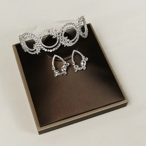 Gros plan sur parure bijoux de mariée argentée avec serre-tête strass et boucles d'oreilles