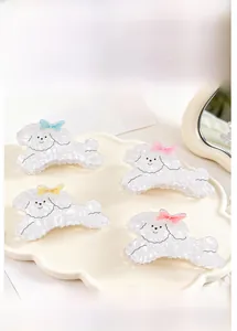 Détail de quatre pinces à cheveux en forme de caniche avec des nœuds colorés sur un plateau