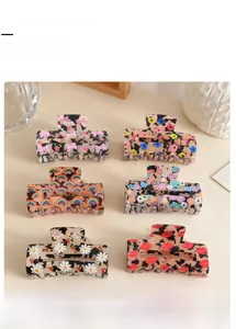 Detail view of large hair claw clips featuring daisy, rainbow, and strawberry prints