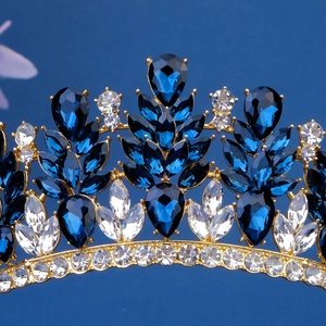 Detailed close-up of golden tiara featuring deep blue and clear marquise crystals