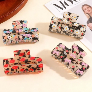 Set of four stylish resin hair claw clips with daisy and floral prints in a fashion setting