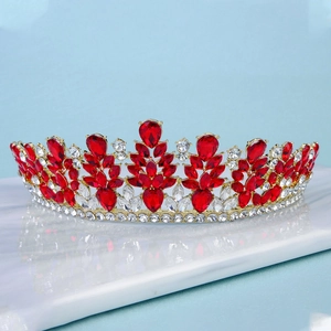 Close-up of a luxury gold bridal crown featuring teardrop red crystals and white rhinestones