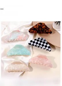 Macro detail of large marble texture and checkered pattern hair claw clips on silk