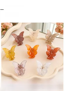 Close-up of 8 colorful translucent resin butterfly hair claw clips on a wavy tray