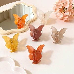 Set of 6 colorful transparent butterfly hair claws in various warm tones on a desk