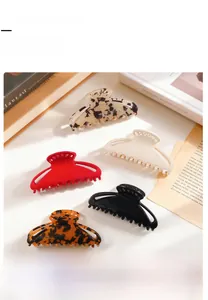 Close-up of hair claw clips in leopard, cream, and amber finishes with metal springs