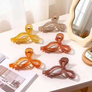 Minimalist resin ribbon hair claw clips in five earthy colors on a stylish vanity table