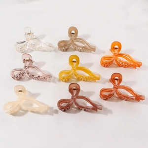 Bow-shaped acrylic hair claws in eight assorted colors on a minimalist white background