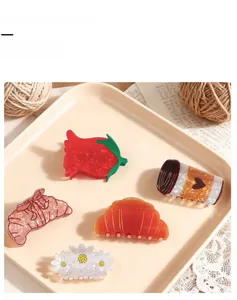 Detailed macro view of creative acetate hair claws featuring strawberry and croissant designs
