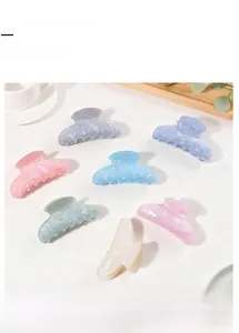 Flat lay of seven pearlescent pastel hair claw clips in macaron colors on a white surface
