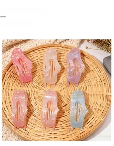 Set of six colorful acetate hair claw clips with marble texture on a woven tray