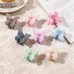 Lot de huit pinces à cheveux papillon mates aux couleurs pastel sur fond en peluche douce