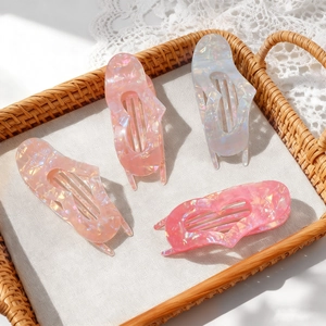 Set of four heart-shaped acetate hair claws with iridescent marble textures and shell finish