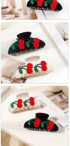 Detailed close-up of cherry pattern hair claw clips in black and cream finishes