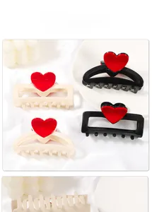Dettaglio delle pinze per capelli con cuore in beige e nero su uno sfondo di raso