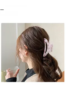 Pince à cheveux lilas en acétate avec texture marbrée portée sur cheveux ondulés