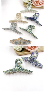 Detail of large marble texture hair claw clips on wooden tray with floral accents