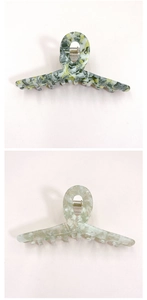 Detailed view of large marble texture hair claw clips in green and dark patterns