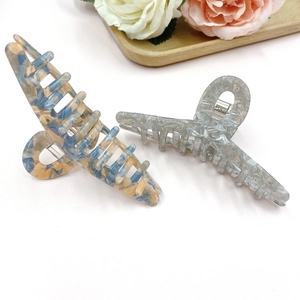 Set of two large marble and tortoiseshell hair claw clips on a decorative wooden tray
