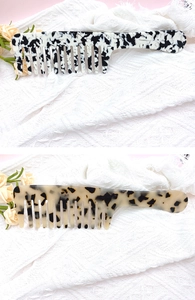 Detail of marble and amber leopard print acetate wide-tooth combs on white textile