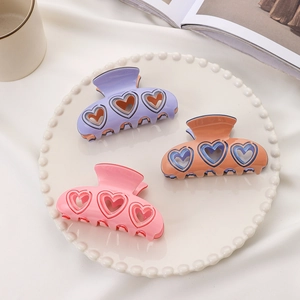 Trois pinces à cheveux coeur évidé en violet pastel, orange pêche et rose doux