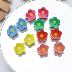 Set of 2cm colorful flower resin hair claws arranged on a mirror reflecting bright colors