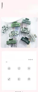 Detail of rectangular hair claws in leopard print and green clover patterns on a newspaper