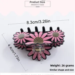Détail d'une pince à cheveux noire de 8cm avec marguerites roses et ressort en métal